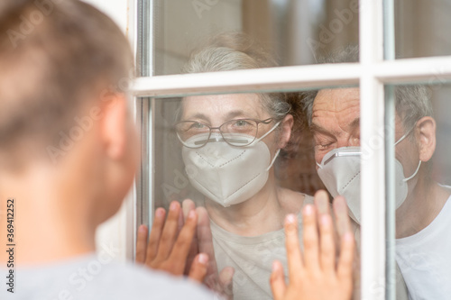 Boy communicates with his grandparents through a window during the coronavirus epidemic