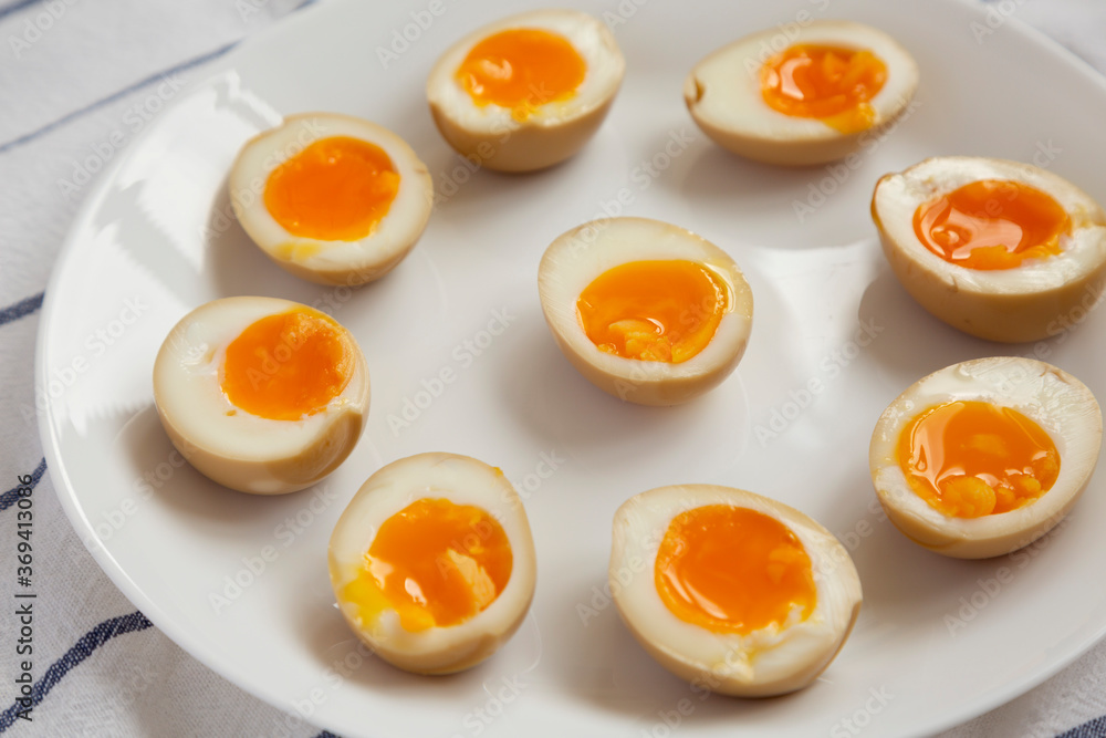 Homemade Unami Soy Sauce Eggs on a white plate, low angle view. Close-up. Homemade Unami Soy Sauce Eggs on a white plate, low angle view. Close-up.