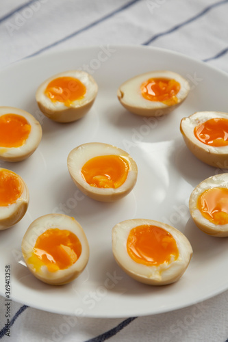 Homemade Unami Soy Sauce Eggs on a white plate, low angle view.