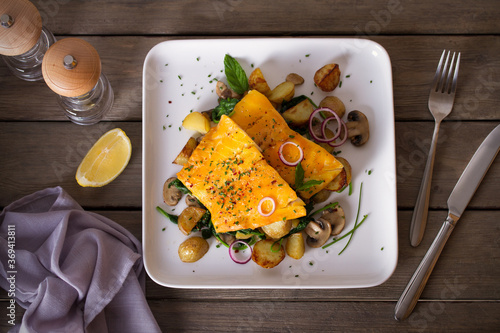 Cod fish fillets with potatoes, mushrooms and spinach on white plate. Overhead horizontal photo