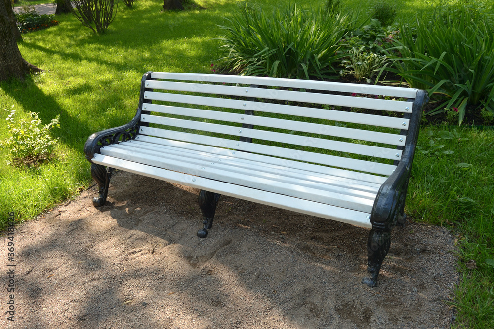 White bench in the park against the background of green bushes. White bench in the park against the background of green bushes.