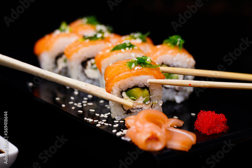 Sushi with salmon. Soy sauce, red caviar. Sushi on a black background.