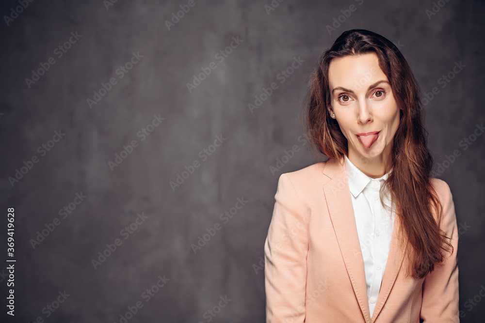 Adult woman sticking out tongue on dark background Adult woman sticking out tongue on dark background