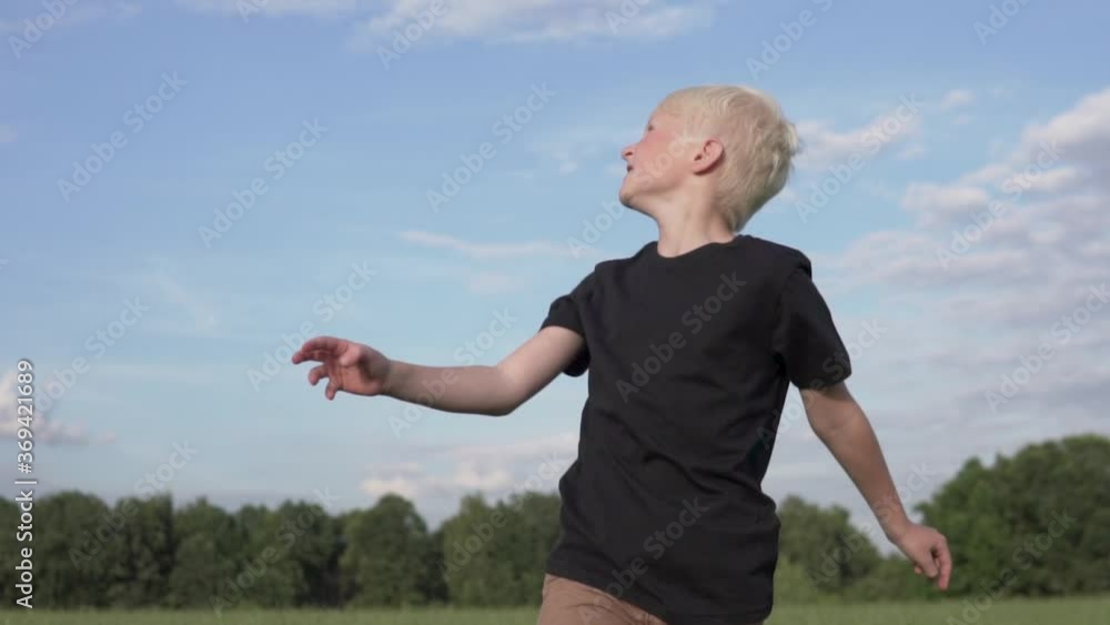 A handsome blonde boy launches a toy plane into the sky in the summer in a green field. A handsome blonde boy launches a toy plane into the sky in the summer in a green field.