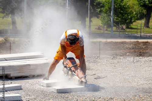 Worker cutting granit stone with circular hand saw photo