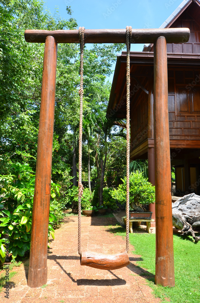 High wooden swing with Thai style house and trees background High wooden swing with Thai style house and trees background
