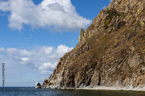 Big cliff at Baikal lake shore in summer with blue sky and clouds