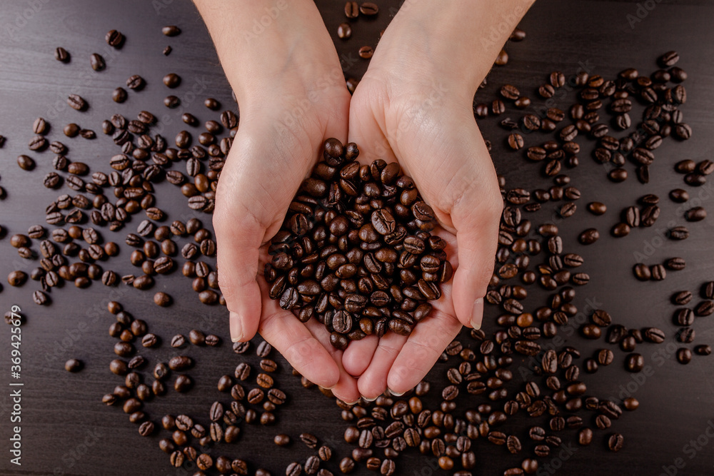 Obraz premium Mani che sorreggono dei chicchi di caffè appena tostati