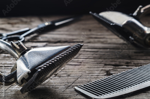 On a old wooden surface are old hairdresser tools. two vintage hand-held hair clipper and comb and seen hairdressing scissors. horizontal