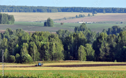 A tractor with a plow plows a rural field. Agricultural work in the economy of the village of Bogorodsk (Oktyabrsky district of Perm region) photo