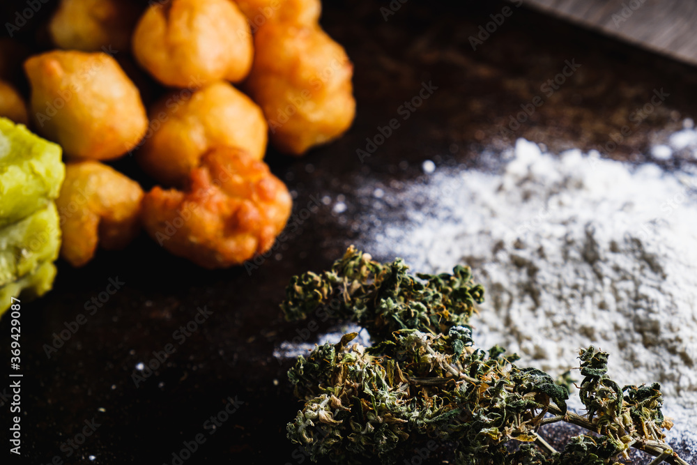 churros balls spanish donuts from medical cannabis butter, sugar, flour, egg. Nearby are marijuana buds. cannabis butter, a heap of flour. On a rusty baking sheet. horizontal. churros balls spanish donuts from medical cannabis butter, sugar, flour, egg. Nearby are marijuana buds. cannabis butter, a heap of flour. On a rusty baking sheet. horizontal.