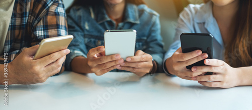 Group of young people using and looking at mobile phone while sitting together photo