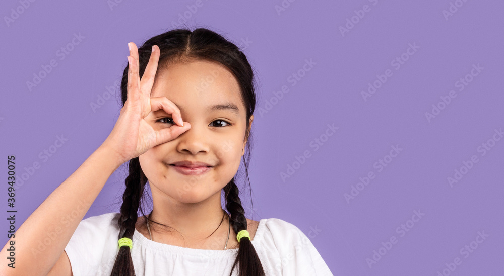 Asian Girl Covering Eye With OK Sign Posing In Studio Asian Girl Covering Eye With OK Sign Posing In Studio