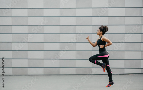 Runner on track after workout. African american girl in sportswear and with fitness tracker, jogging