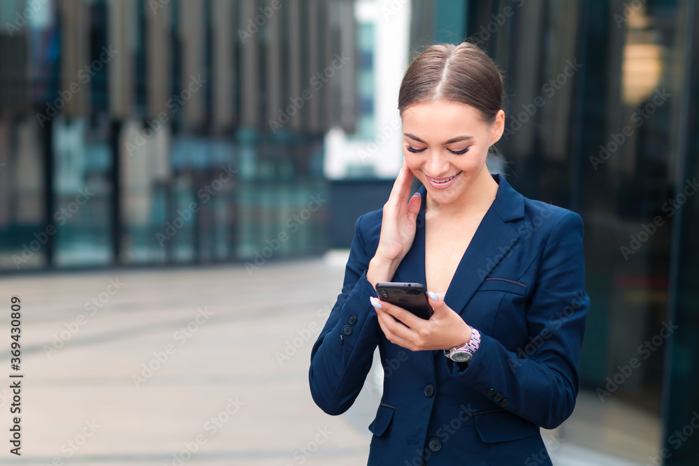 Beautiful happy businesswoman looking at her cell mobile phone, typing or reading a message. Young glad positive girl, pretty woman chatting in social media on her smartphone, smiling. Good news. Beautiful happy businesswoman looking at her cell mobile phone, typing or reading a message. Young glad positive girl, pretty woman chatting in social media on her smartphone, smiling. Good news.