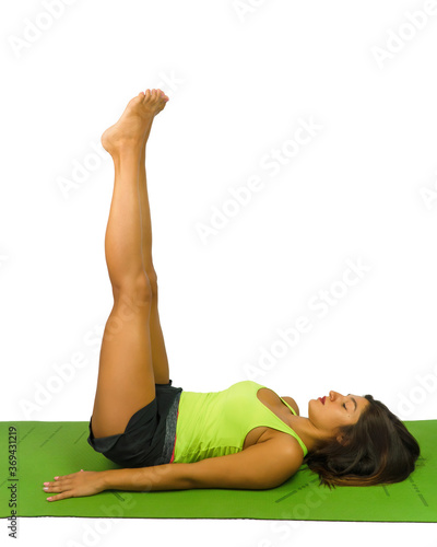 A beautiful girl in shirt and shorts practices pilates at home on a green mat with legs raised to 90 degrees. Photos on a white background.
