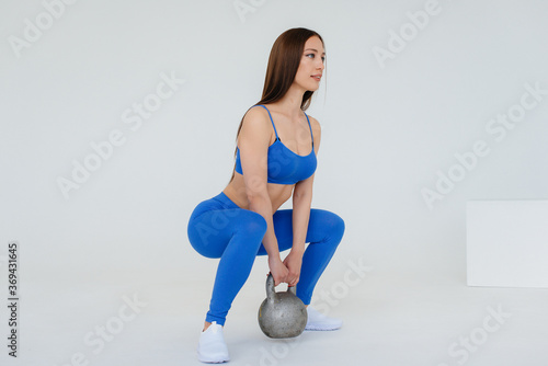 Sexy young girl performs sports exercises on a white background. Fitness, healthy lifestyle