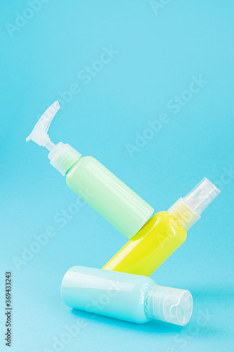 Yellow and blue cosmetic bottles on the same colored background. Stylish concept of organic essences, beauty and health products. Copy space, minimalism, levitation effect.