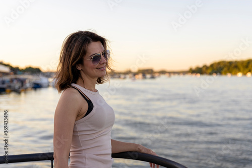 Beautiful woman wearing sunglasses at sunset by the river. Focus on the sunglasses