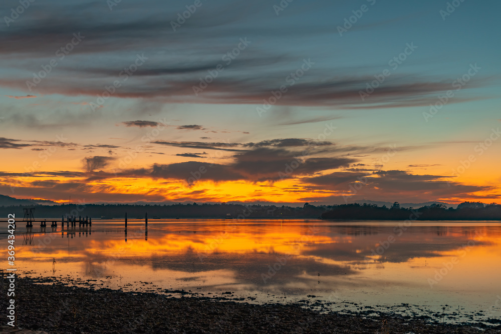 Fototapeta premium Clouds, reflections and sunrise over the bay