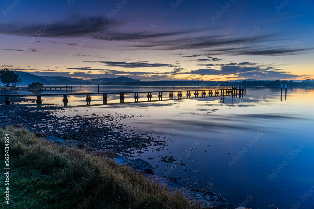Wharf, reflections and sunrise over the bay