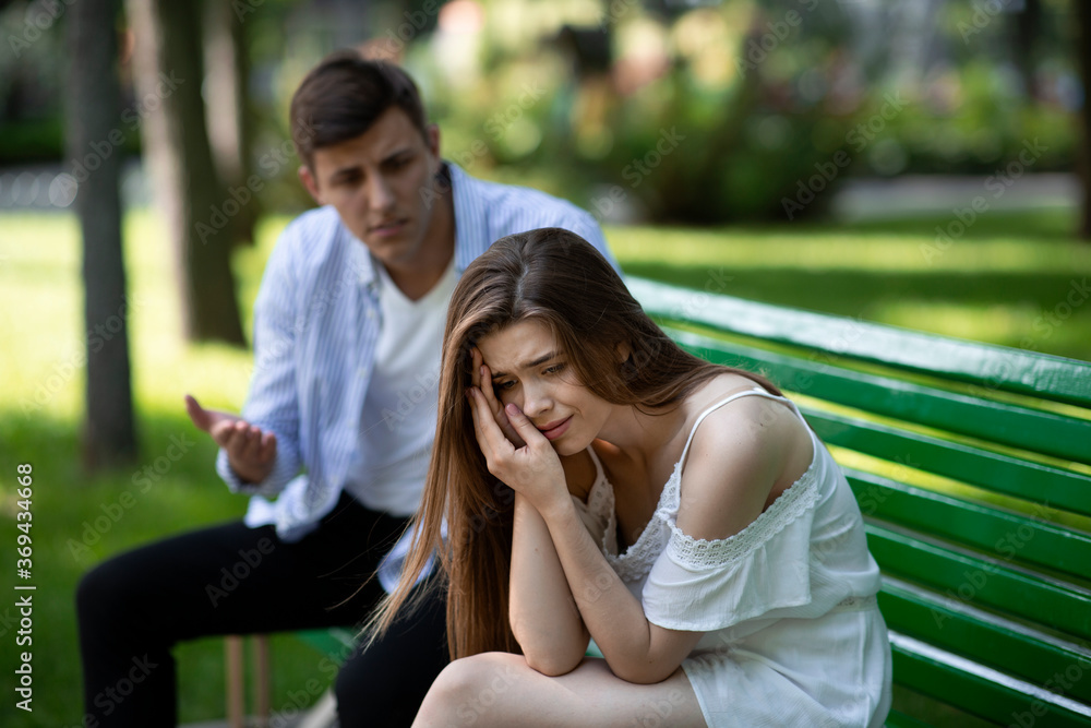 Domestic violence. Angry man and his desperate battered wife on bench at park Domestic violence. Angry man and his desperate battered wife on bench at park