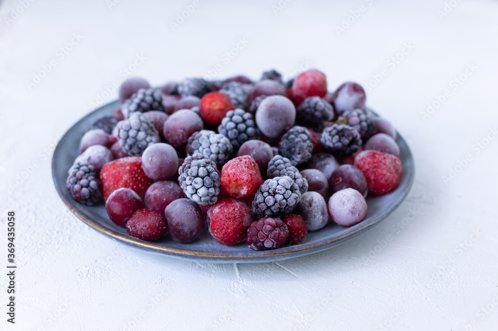 Frozen berries in a gray plate on a white background. Copy space. Close-up. Selective focus. Frozen berries in a gray plate on a white background. Copy space. Close-up. Selective focus.