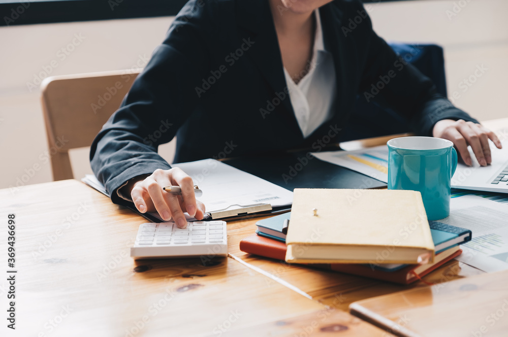 Close up of businesswoman or accountant hand holding pencil working on calculator to calculate financial data report, accountancy document and laptop computer at office, business concept Close up of businesswoman or accountant hand holding pencil working on calculator to calculate financial data report, accountancy document and laptop computer at office, business concept