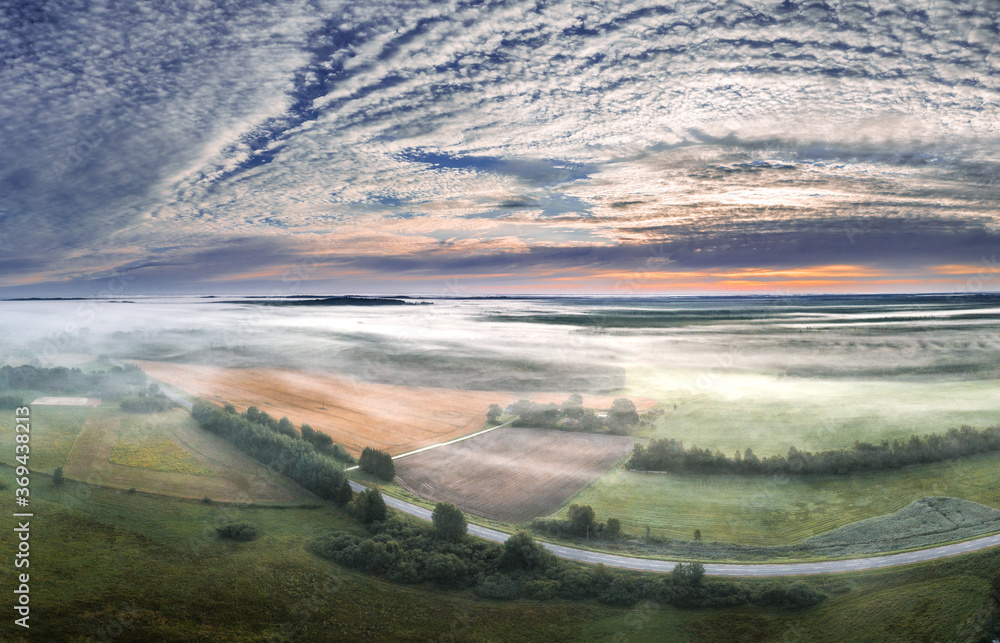 Aerial view of highway leading through a foggy countryside. Beautiful texture in the sky. Aerial landscape. Aerial view of highway leading through a foggy countryside. Beautiful texture in the sky. Aerial landscape.