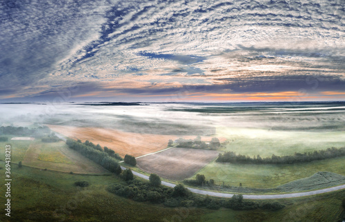 Aerial view of highway leading through a foggy countryside. Beautiful texture in the sky. Aerial landscape.