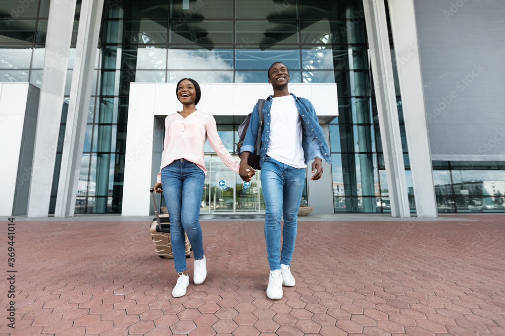 Ready For Adventures. Excited Black Couple Leaving Airport Building In New Country