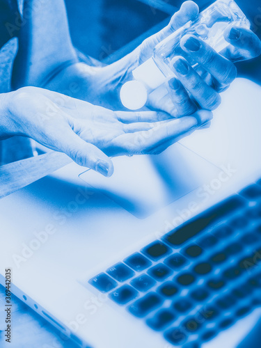 Female brunette latina 40s freelancer employee working at the desk at home office , cleaningher hands with gel, wearing protection mask. photo