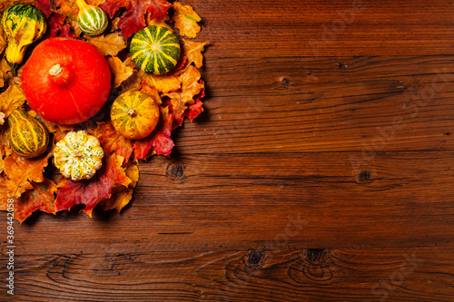 Wooden background. Arranged autumn leaves and pumpkins. Top view.