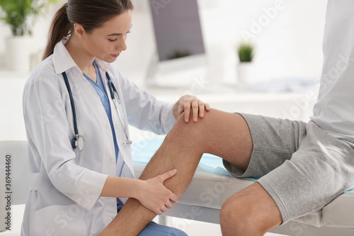 Female orthopedist examining patient's leg in clinic, closeup photo