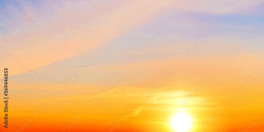 Golden sunset sky landscape background. Natural color of evening cloudscape with setting sun. Orange clouds on yellow sky. Colorful panorama wallpaper. Ultra wide panoramic view. Banner template