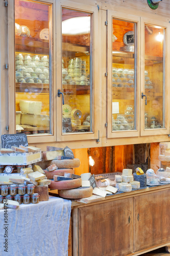 Private cheese shop. Many different types of cheese. Outside the wooden Windows, circles, halves, and quarters of cheese are laid out. Healthy delicious food, variety