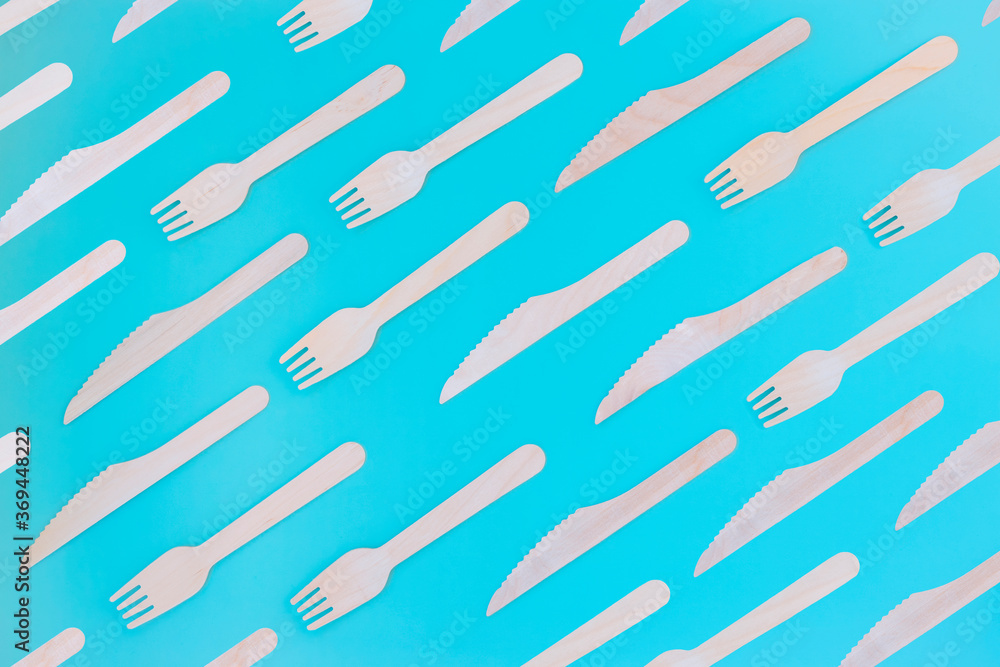 Wooden forks and knives on a turquoise background. Cutlery template. Top view. Wooden forks and knives on a turquoise background. Cutlery template. Top view.