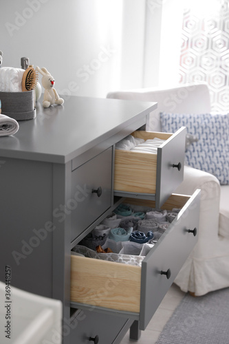 Modern open chest of drawers with clothes and accessories in baby room © New Africa