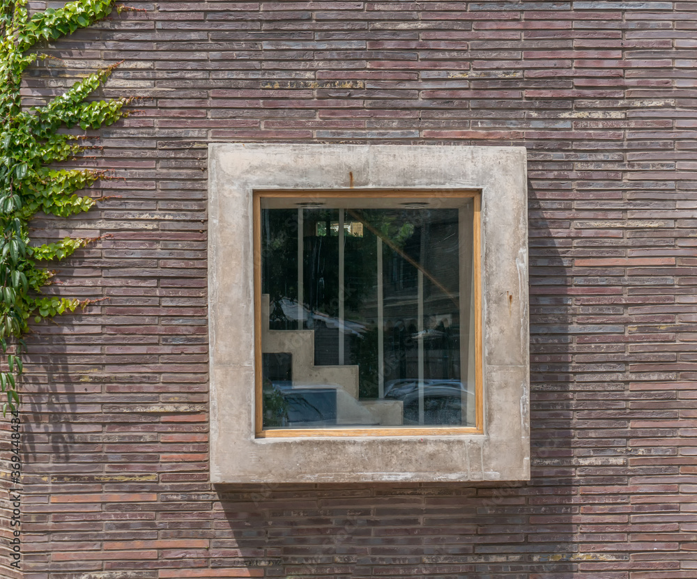 Fototapeta premium A square window with a view of stairs inside set into a red brick building
