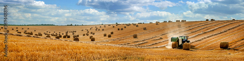 Stampa su tela large panorama of a field with bales of straw, a tractor with a baler harvesting