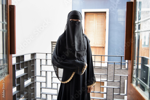 Portrait of Arabian woman covering her face with niqab veil, traditional islamic face mask; concept of social distancing in Muslim culture photo