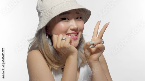 zoom in dolly blonde korean model with thongue out and v-sign hand making faces smiling and have fun in studio on wite photo