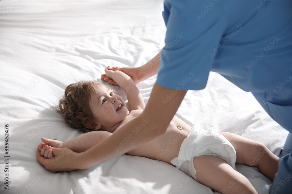 Orthopedist examining cute little baby on bed Orthopedist examining cute little baby on bed