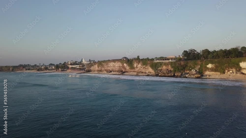 Flying above evening ocean surface, aerial view of foamy waves rolling at rocky shore. Flying above evening ocean surface, aerial view of foamy waves rolling at rocky shore.