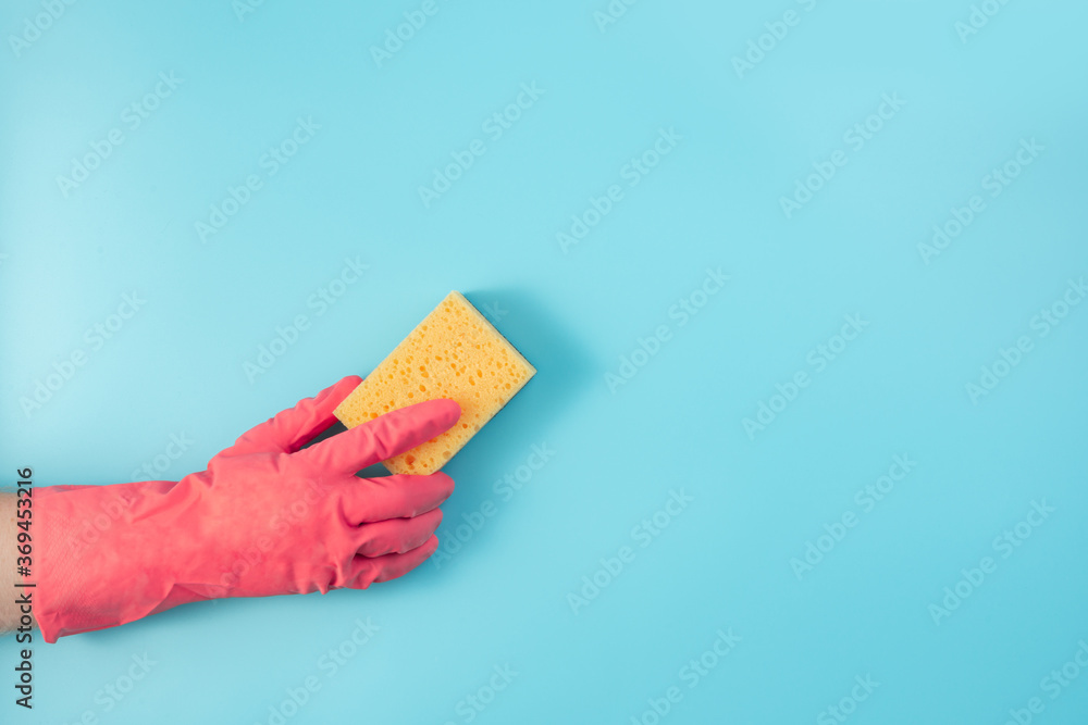 A hand in a red glove wipes the wall from dust with a yellow sponge. A hand in a red glove wipes the wall from dust with a yellow sponge.