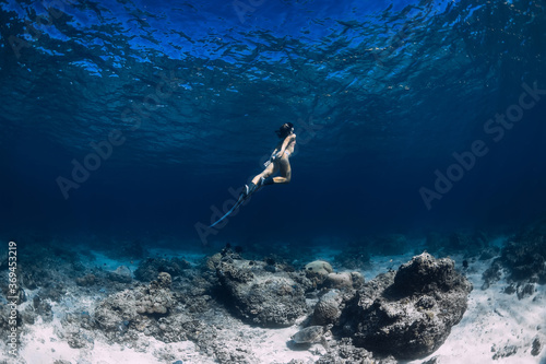 Woman freediver glides underwater in sea. Freediving with fins