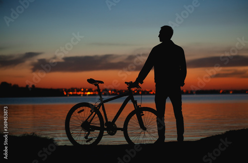 Man is enjoying watching sunset on the riverside all by himself © Amelia Fox