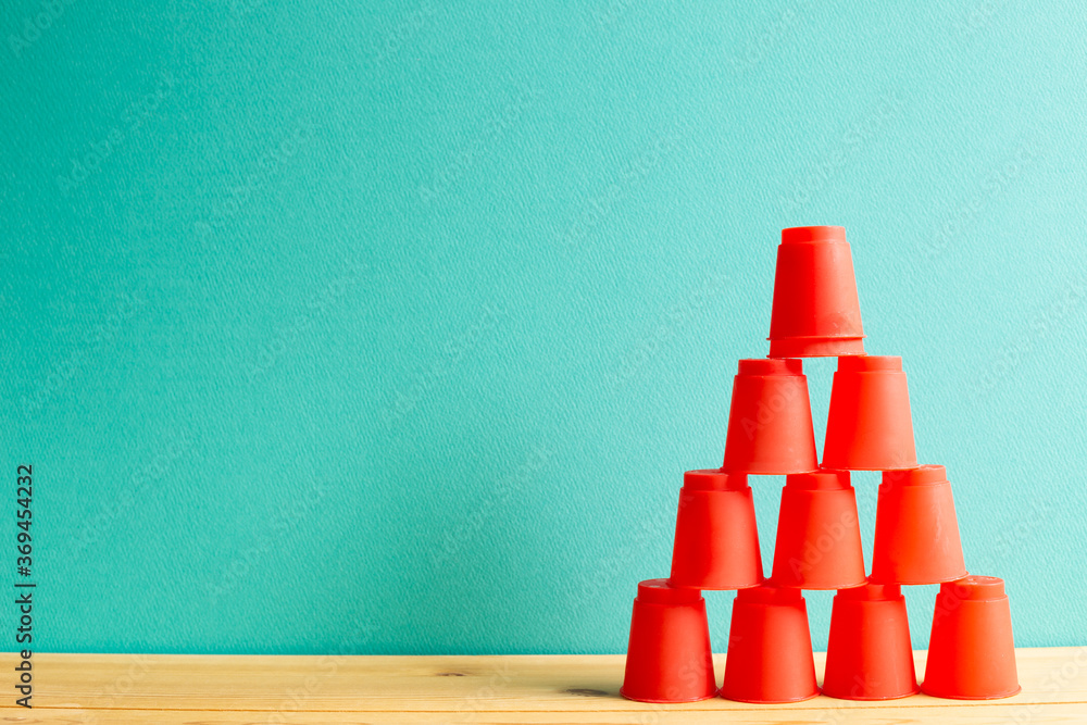 Pyramid of red plastic cups on wooden table with green background