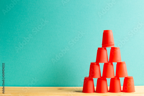 Obraz na płótnie Pyramid of red plastic cups on wooden table with green background w salonie