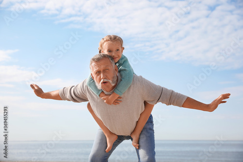 Little girl playing with grandfather on sea beach
